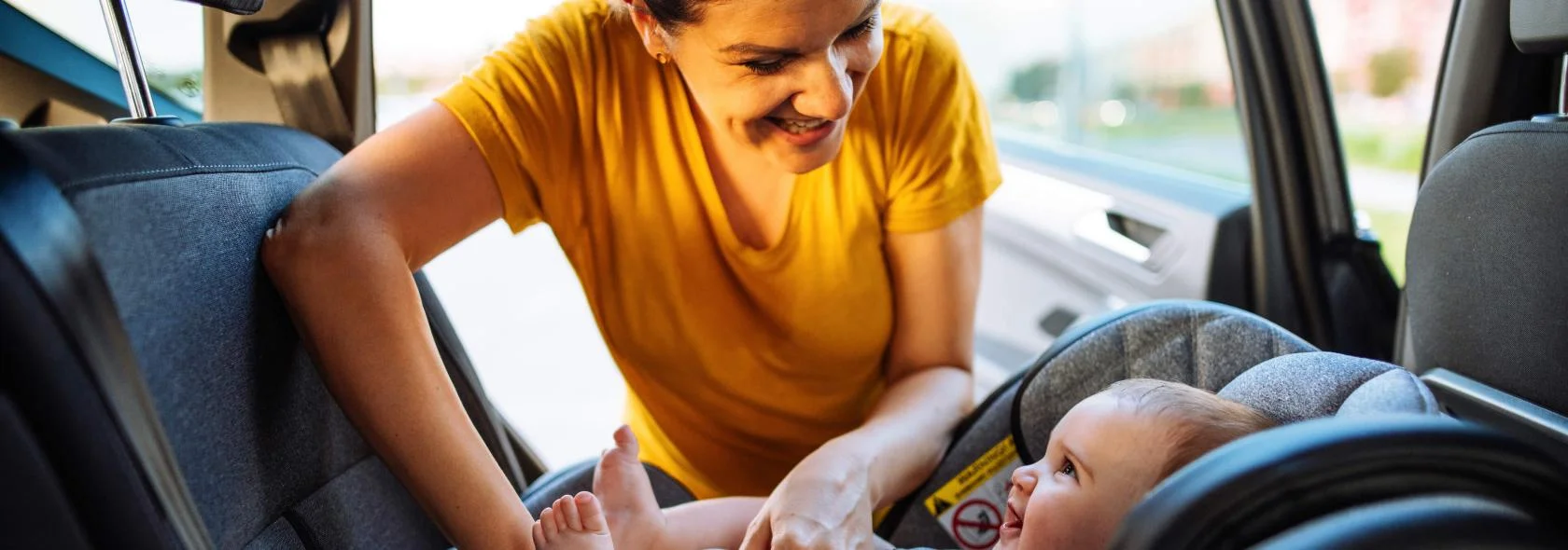 A woman securing her baby's carseat