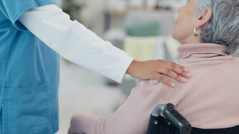 Hospital Volunteer comforting an elderly female patient who is in a wheelchair