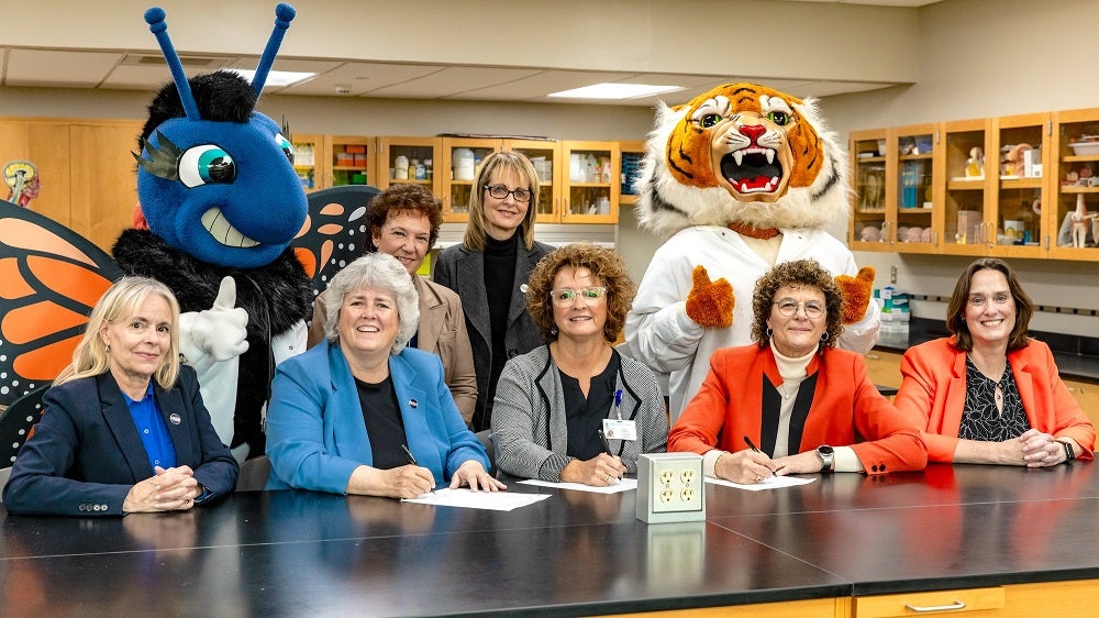 Maria College's mascot & leadership sitting with Bassett's Chief Nursing Executive and SUNY Cobleskill's mascot & leadership, signing the partnership agreement