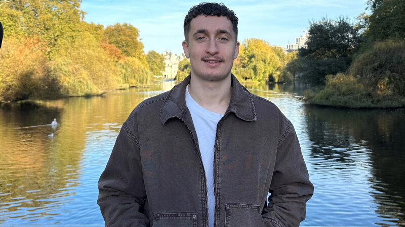 Dakota Basloe stands in front of a lake.