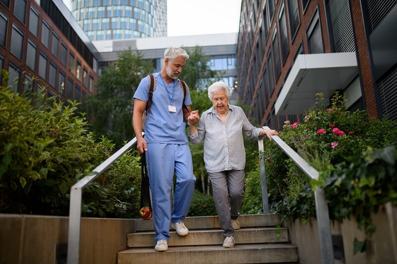 Occupational Therapist helping an elderly patient not fall down the stairs