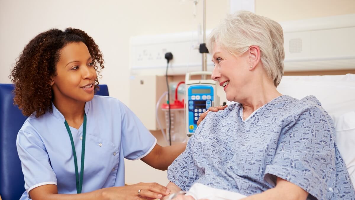 Nurse sitting with an elderly woman patient in the hospital