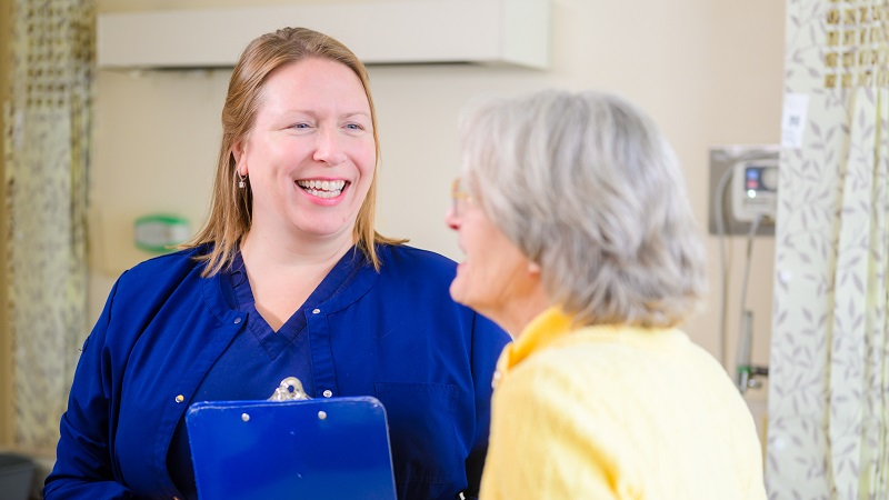 Bassett nursing smiling while helping an elderly patient