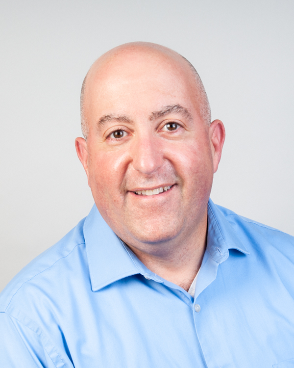A man in professional attire is photographed from the shoulders up.