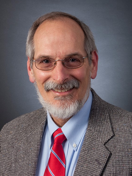 A man, Dr. Chris Kjolhede, is photographed wearing a suit and tie.