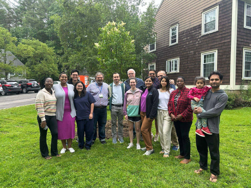 15 people are photographed outside. They are standing in front of a tree. Dr. Timur Otajonov is in the middle of the group.